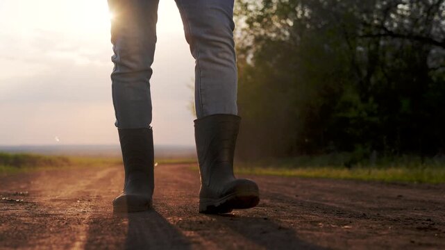 Person walking down dirt road. Man working on his boots in a lifestyle field. Close up of a farmer walking his legs up a road. An individual strolling along a gravel path.