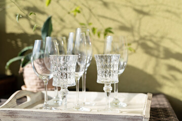 Empty glasses made from crystal prepare for celebretion outdoor. Shadow on the wall in summer....