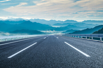 Naklejka premium Empty asphalt highway road and continuous rolling mountain range natural landscape in the morning
