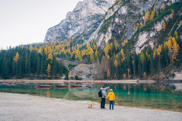 Father and son enjoying a peaceful moment at a tranquil lake surrounded by autumn trees in the mountains on a cool day