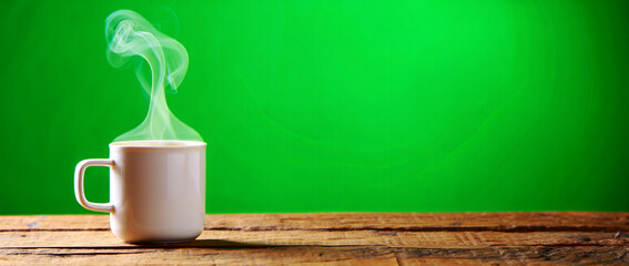 Warm ceramic mug on a rustic wooden table with gentle steam rising against a vibrant green background, perfect for a cozy morning or comforting break moment