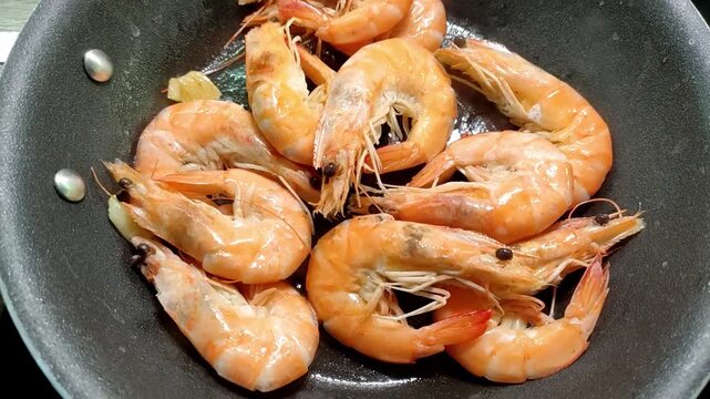 Chef frying king prawns in a pan