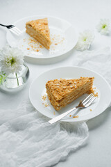 Napoleon cake layers with pastry cream, served on plates with forks and flowers