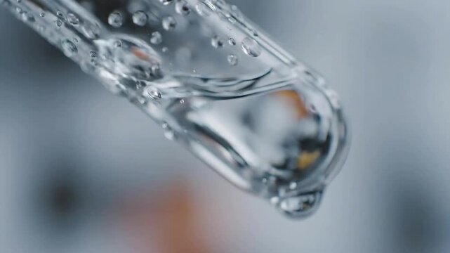 Close Up of Liquid Dropping from Clear Glass Pipette in Laboratory Setting for Scientific Experimentation Research and Cosmetic