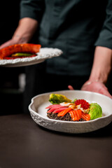 A chef holds a freshly prepared poke bowl with salmon, tuna, avocado, and quinoa, ready to be...