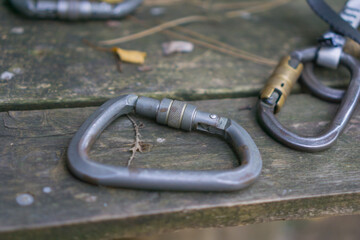 screw lock safety carabiner resting on a rough textured gray wooden table, metal climbing equipment in an outdoor adventure setting, concept of security, risk, durability, concept of sports, rescue