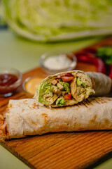 Fresh grilled chicken wrap with lettuce and tomatoes on wooden board