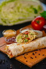 Delicious grilled chicken wrap with fresh vegetables on wooden board