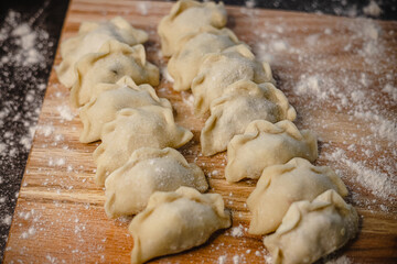 Homemade raw dumplings on floured wooden surface