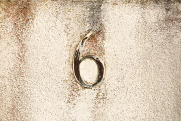 Weathered number 6 engraved on an aged concrete wall. Grunge urban detail with vintage tone and textured background for design or architecture use