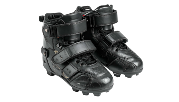 Pair of black high-top footwear with straps, against black backdrop