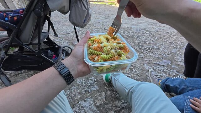 Escena natural y relajada de una familia comiendo pasta a la sombra en Siurana, Tarragona. Grabado desde la perspectiva en primera persona, se aprecia un momento cotidiano de descanso durante el d&iacute;a