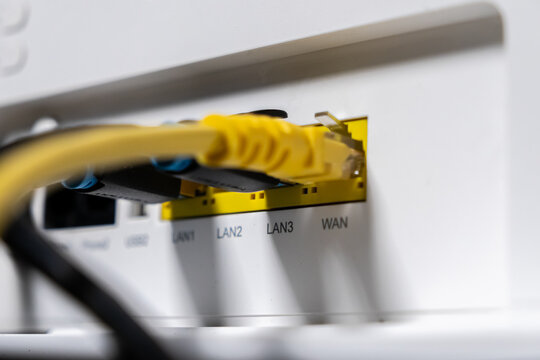 White internet router's back panel showing yellow and black Ethernet cables plugged into LAN and WAN ports, essential for fast, reliable home and office network connections