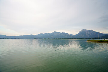 Tranquil water reflects towering mountain range in the distance during a cloudy afternoon at...