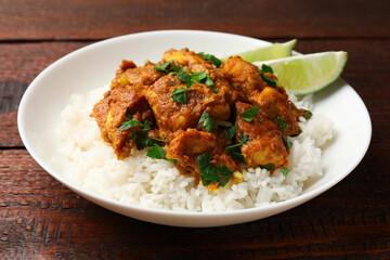 Fototapeta premium Chicken tikka masala with rice served on wooden table, closeup