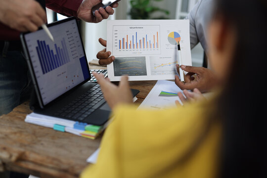 Business people analyzing financial charts and graphs on digital tablet and paper reports, discussing company performance and making strategic decisions using both digital tablet and printed reports.