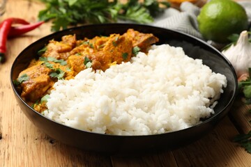 Chicken tikka masala with rice and spices on wooden table, closeup