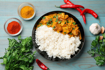 Chicken tikka masala with rice and spices on light blue wooden table, flat lay