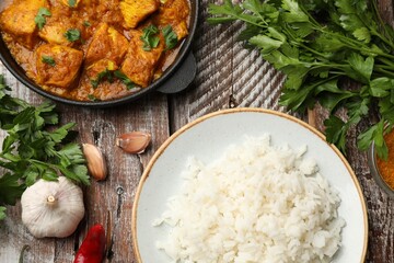Chicken tikka masala with rice and spices on wooden table, flat lay