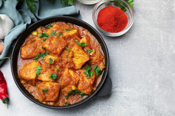 Chicken tikka masala with spices on grey table, flat lay. Space for text