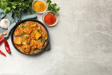 Chicken tikka masala with spices on grey table, flat lay. Space for text
