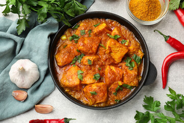Chicken tikka masala with spices on grey table, flat lay