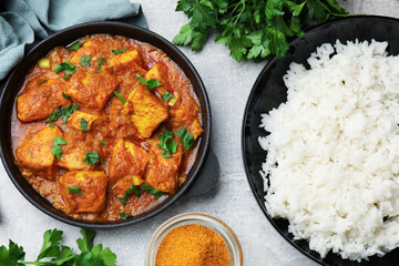 Chicken tikka masala with rice and spices on grey table, flat lay