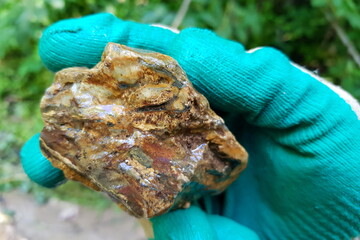 Raw flint fragment clutched in a gloved hand, its unique earthy patterns and rugged texture unearthed