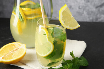 Fresh lemonade with lemon, jug and mint on black table, closeup