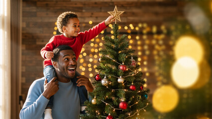 Happy black father helping his son decorate a christmas tree at home. Joyful african american boy on dad's shoulders putting a star on top. Family holiday tradition and celebration