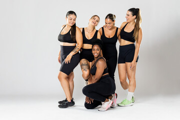 Full photograph of a group of 5 girls of different ethnicities wearing black sportswear posing...
