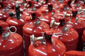 A row of red fire extinguishers, top view. Seals and safety checks, levers and metal cylinders, a tight layout in the warehouse.