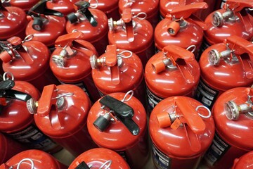 A row of red fire extinguishers in close-up. Metal housings, seals and checks, industrial warehouse, fire safety equipment.