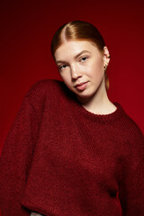 Fototapeta premium Red-haired young woman showcases winter fashion against a vibrant background