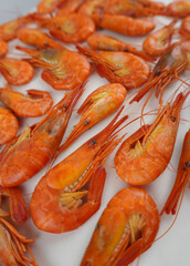 Boiled orange shrimp on a light background. Oblique perspective, shallow depth of field. Culinary layout for menus and food stands.