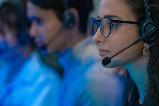 Customer support team in a modern call center receiving guidance from a supervisor. Diverse employees working with headsets and computers, representing teamwork, communication,  business technology.