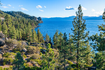 Scenic view of Lake Tahoe California USA with evergreen pine forest and rocky shoreline under clear blue sky on a sunny day in Sierra Nevada mountains showing natural beauty of alpine wilderness