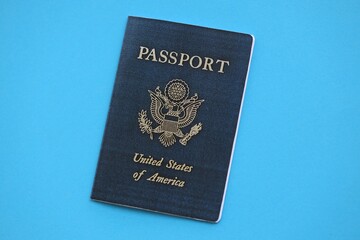 United States passport book on light blue paper background close up. Travel document on blue surface