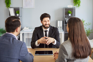 Agent, couple client serious discussion at desk, attentive sell, buy advising, listening on formal...