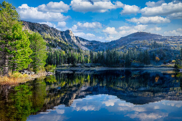 Lily Lake near Fallen Leaf Lake at Lake Tahoe California USA with calm water reflecting pine forest rocky mountains and blue sky with white clouds in scenic Sierra Nevada landscape on sunny autumn day