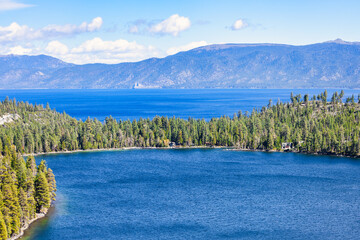 Scenic view of Cascade Lake near Emerald Bay at Lake Tahoe California USA with deep blue water surrounded by dense pine forest and Sierra Nevada mountains under bright clear summer sky