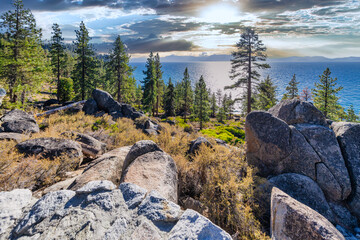 Lake Tahoe Nevada USA scenic viewpoint with pine trees rocks and sparkling blue water under bright sunlight view of Sierra Nevada mountains peaceful nature landscape with clear lake