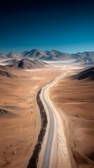 Naklejka premium Journey through the Majestic: An aerial view of a winding road carves its way through a vast, arid landscape, hinting at adventure and exploration beneath a brilliant blue sky.