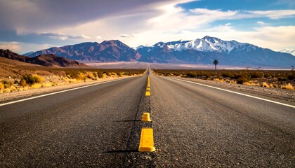 A breathtaking view of an endless desert highway stretching towards majestic snow-capped mountains under a dramatic cloudy sky, symbolizing journey, freedom, and the call of the open road