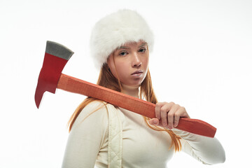 Young redhead woman in a fur hat showcasing her cozy winter style with an axe