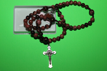 ​A rosary featuring round, natural pink-brown stone beads and a silver-toned metal crucifix is...
