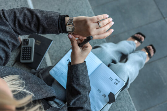 Woman checking the time while planning her schedule in a notebook - Powered by Adobe