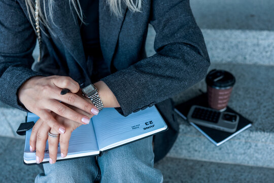Woman checking the time on her watch while sitting on outdoor steps