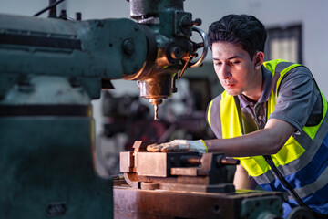A skilled technician works attentively on a heavy duty machine in an industrial workshop. Dressed in safety gear, he demonstrates focus, precision, and craftsmanship in a professional environment.