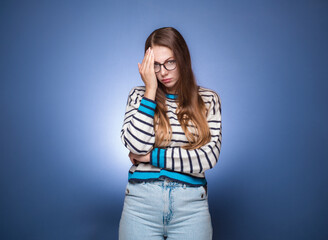 Ashamed woman covering face with hand. Shame, isolated on blue background. Guilty girl.